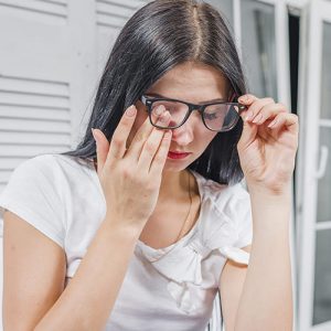 Fotografía de un paciente con lentes y malestar en sus ojos