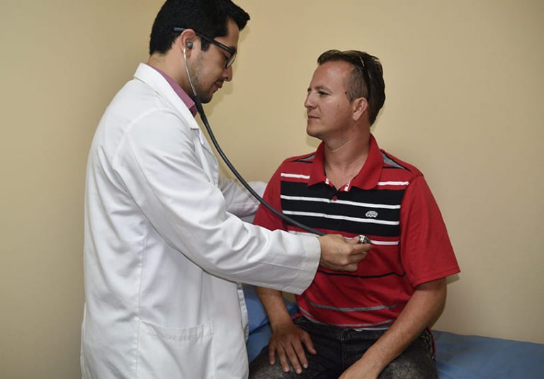 fotografía de nuestro medico internista atendiendo a un paciente utilizando un estetoscopio para verificar su ritmo cardiaco