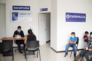 Fotografía de Recepción clínica de san marcos, colaborador tomando datos a pacientes mientras los demás pacientes esperan su turno para ser atendidos